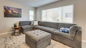 A living room with a sectional sofa, ottoman, small table, and a painting on the wall. - Home Near Air Force, Great Wolf, Ford Amphitheater (Colorado Springs)
