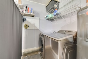 A laundry room with a washing machine, a drying rack, and a pegboard with various items.