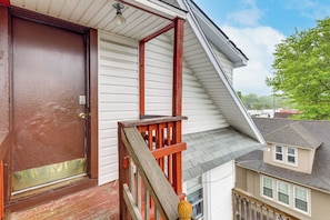 A residential building with a brown front door, a wooden staircase, and a white exterior.