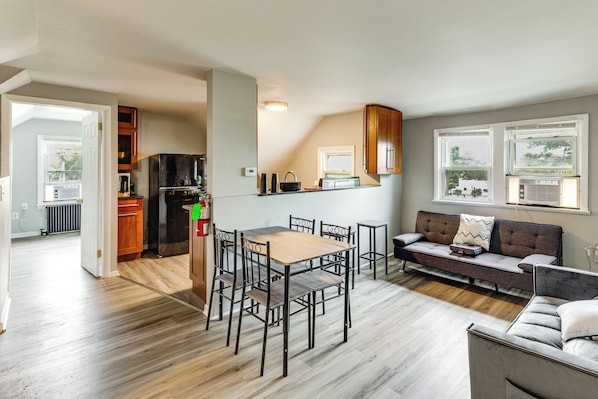 Una cocina moderna con refrigerador, estufa y comedor con sillas y una mesa.