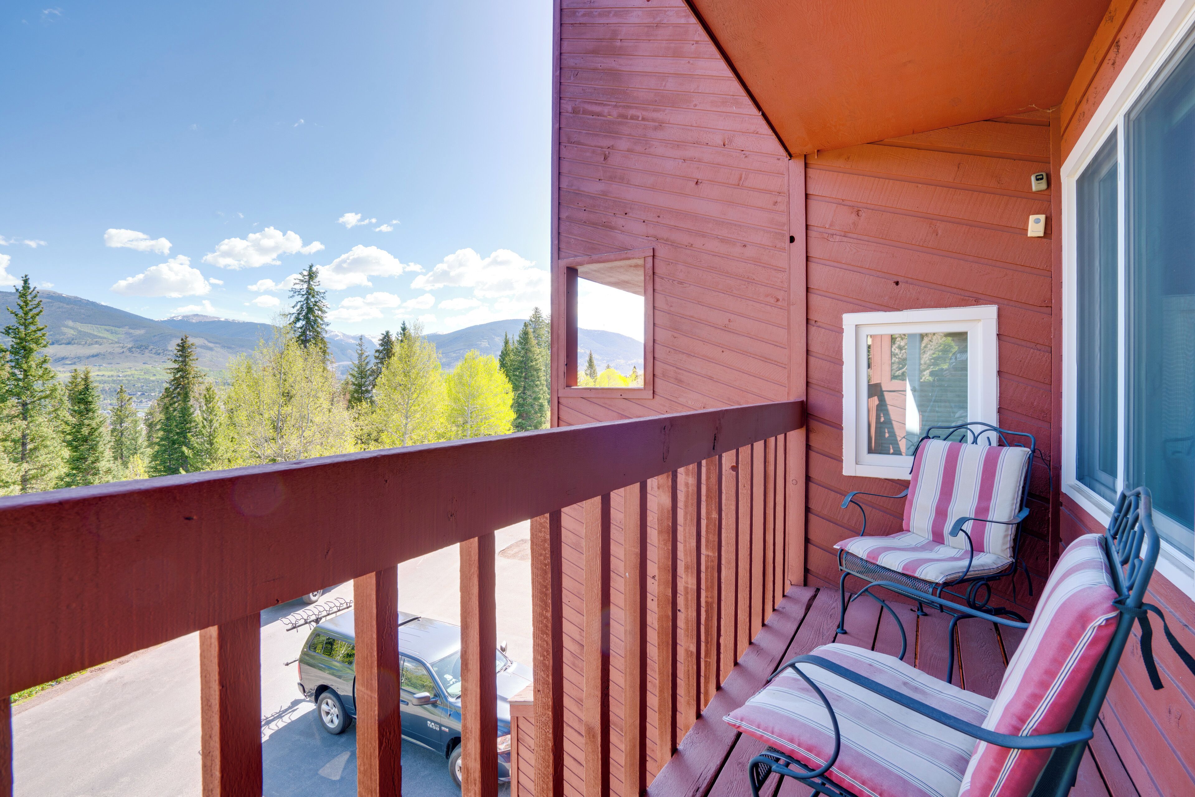 A wooden balcony with two chairs and a view of a mountain range.