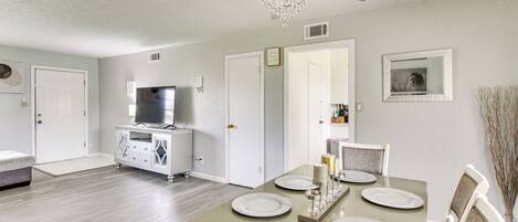 A dining area with a table set for four, a ceiling fan, and a chandelier.