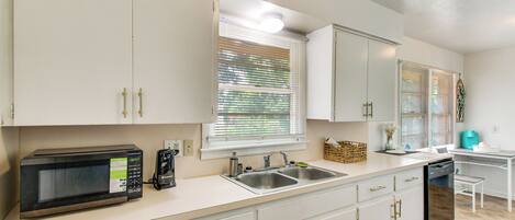 A kitchen with white cabinets, a microwave, a sink, and a dishwasher.