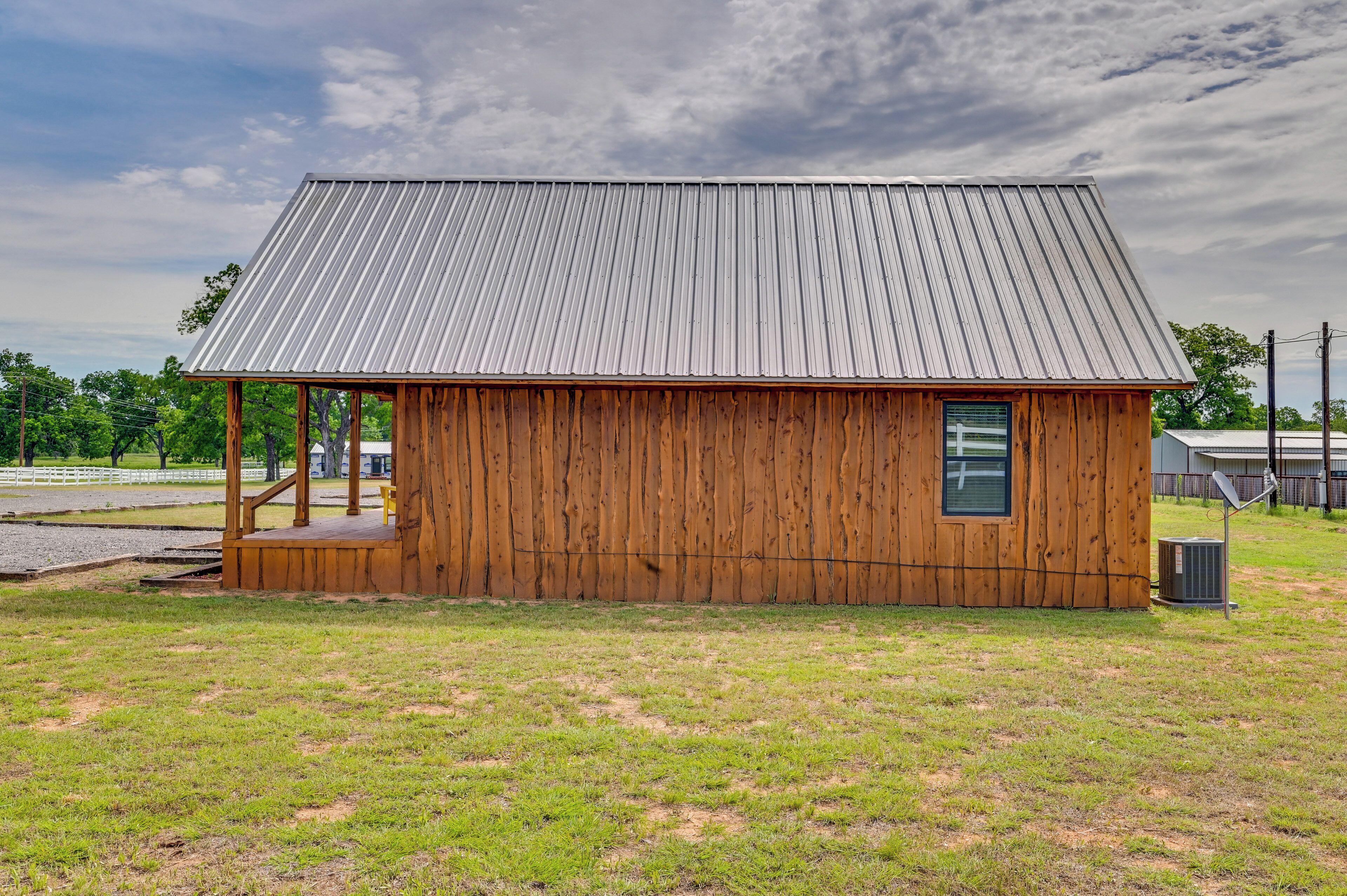 A small wooden building with a metal roof, a porch, and a small window.