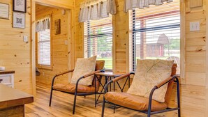 A wooden interior with two leather chairs, a wooden table, and a window with blinds. - Idyllic Farm Setting! Granbury 'white Daisy Cabin' (Granbury)