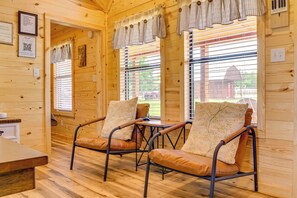 A wooden interior with two leather chairs, a wooden table, and a window with blinds. - Idyllic Farm Setting! Granbury 'white Daisy Cabin' (Granbury)