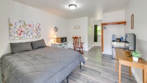 A bedroom with a bed, a desk, a chair, a television, and a kitchen area. - Boat, Fish & Hike! All-season Schroon Lake Getaway (Schroon Lake)