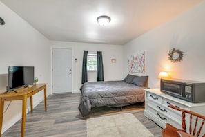 A bedroom with a bed, TV, dresser, and microwave.