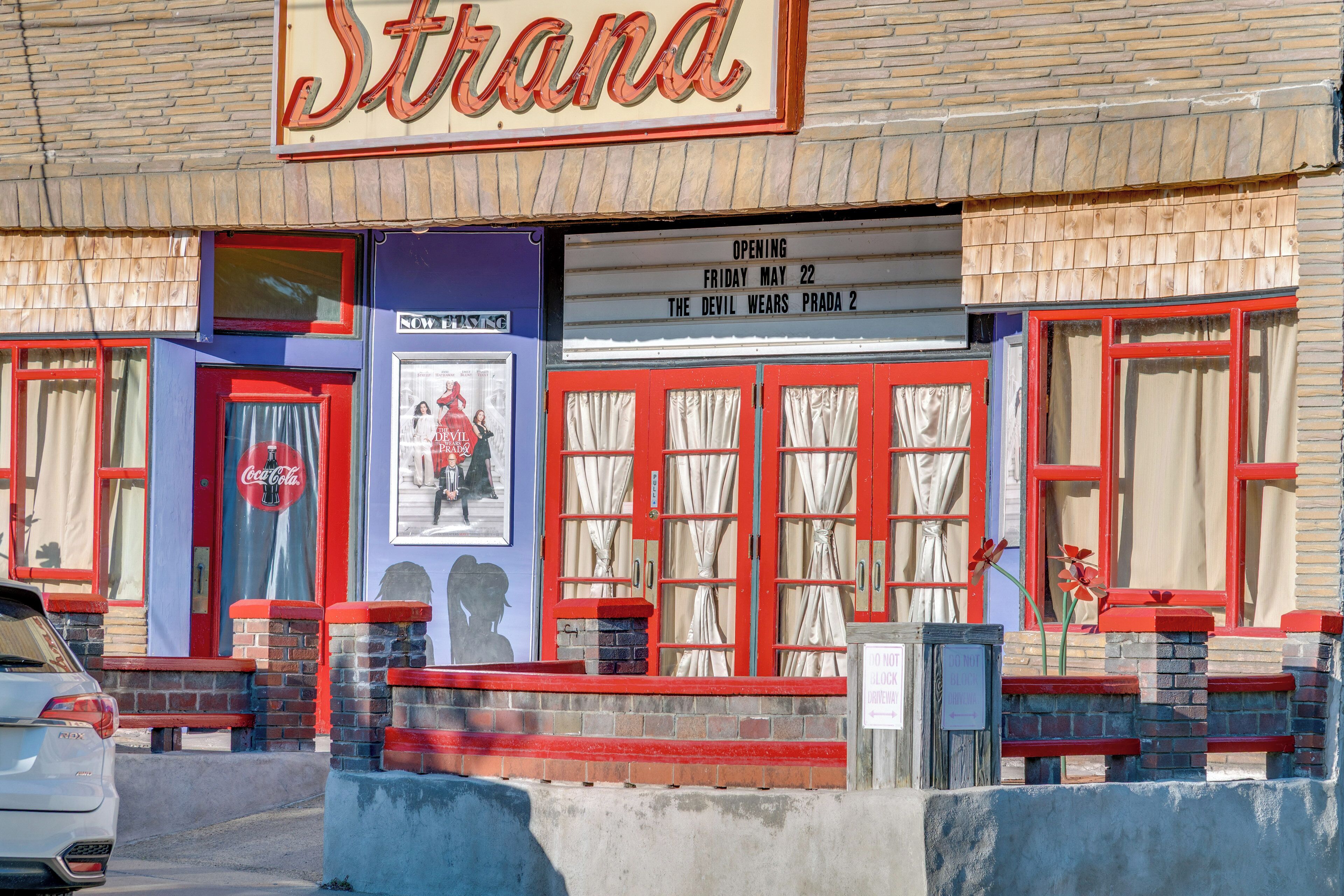 A building with a marquee sign reading 'Strana' and a poster advertising 'The Devil Wears Prada 2' opening on May 22.