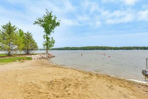 Una playa con arena, árboles y un lago.