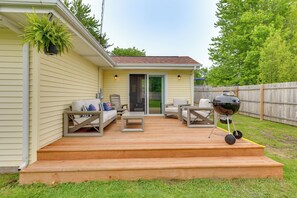 Una terraza con mobiliario exterior, una parrilla y un macramé colgante.