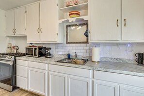 Une cuisine avec des meubles blancs, un four à micro-ondes, une cuisinière et un évier.