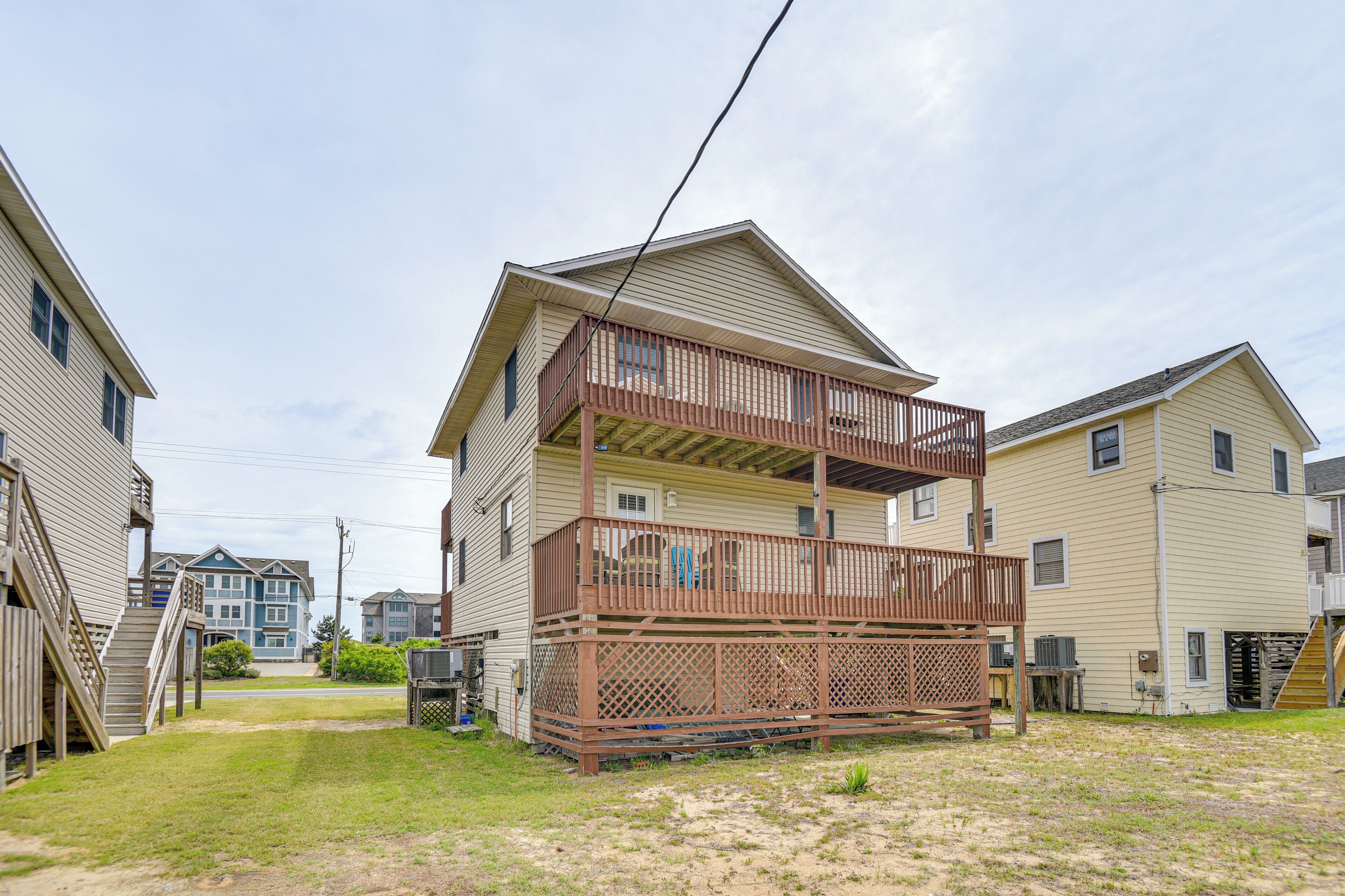 A two-story residential building with a balcony, a small front yard, and neighboring houses.