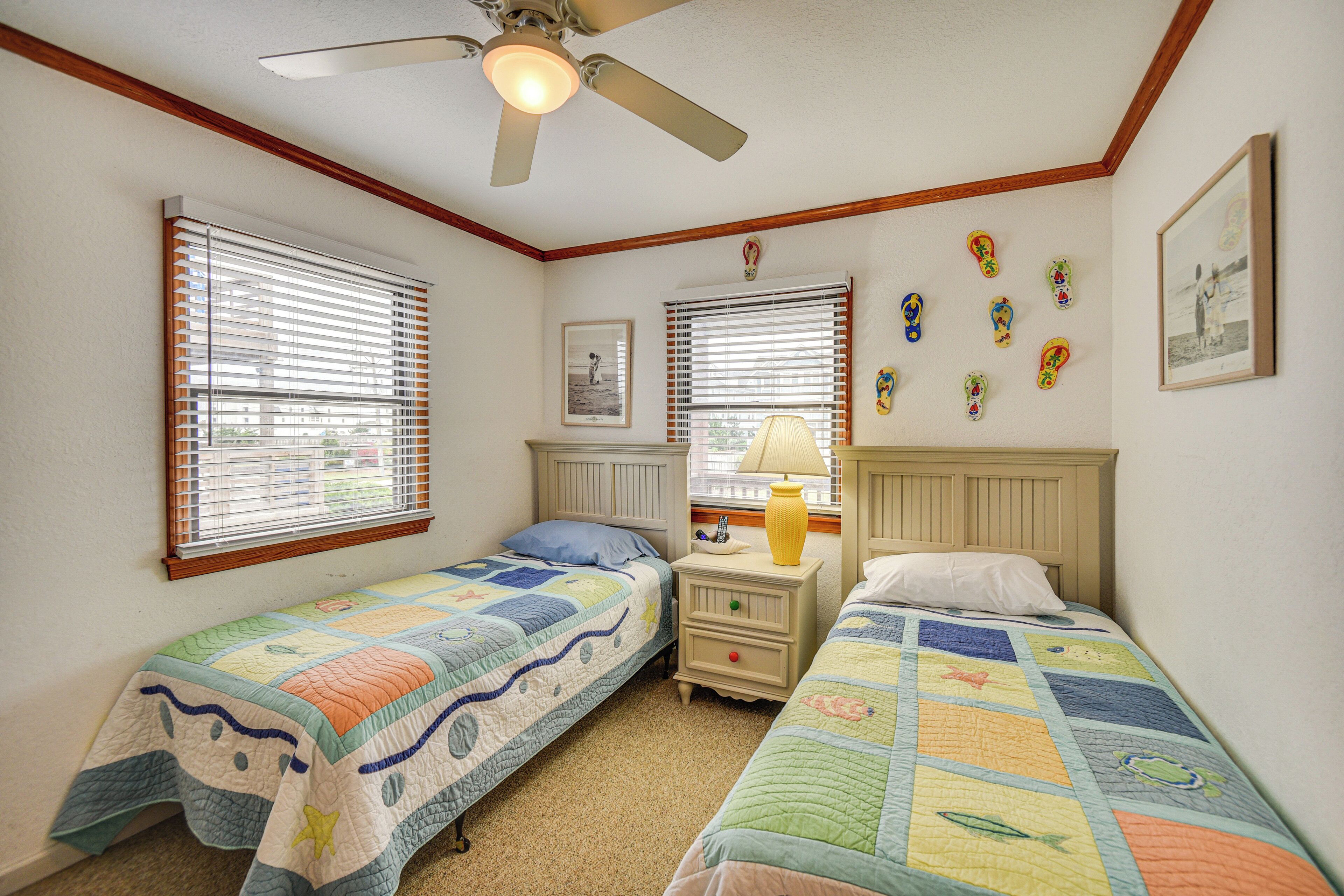 A bedroom with two single beds, a ceiling fan, and a window with blinds.