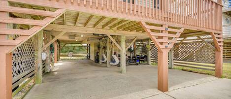 A covered outdoor area with a wooden deck, concrete floor, and a lattice fence.