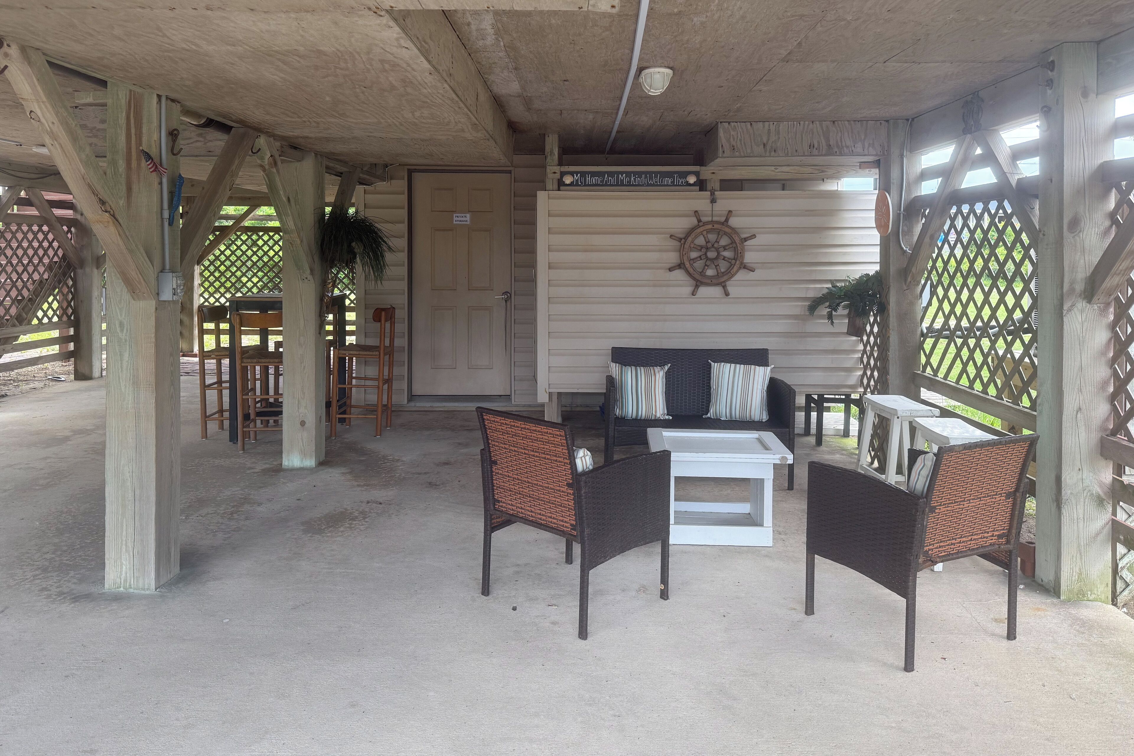 A covered outdoor seating area with wicker chairs, a white table, and a sofa.