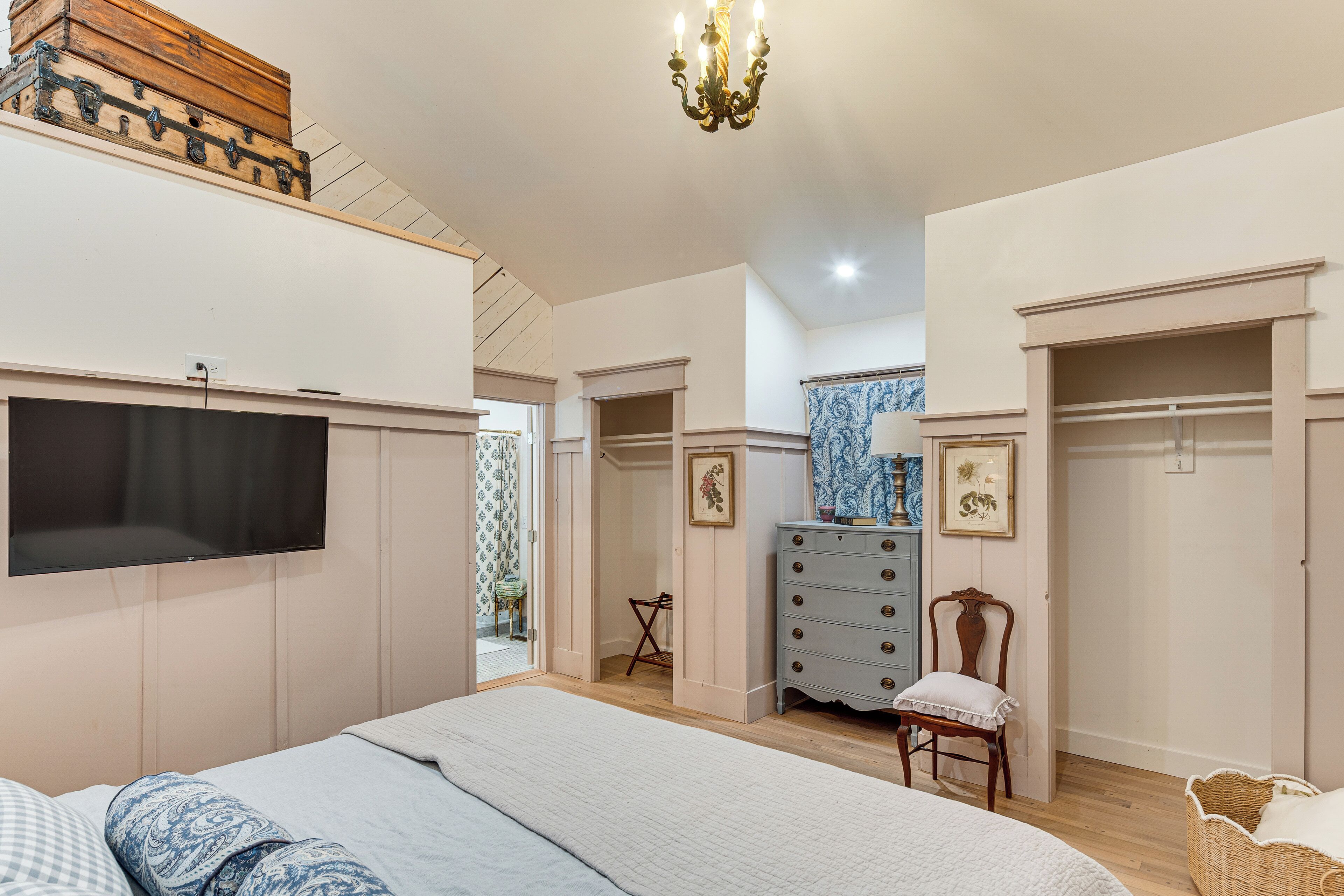 Un dormitorio con cama, cómoda, televisor y candelabro.
