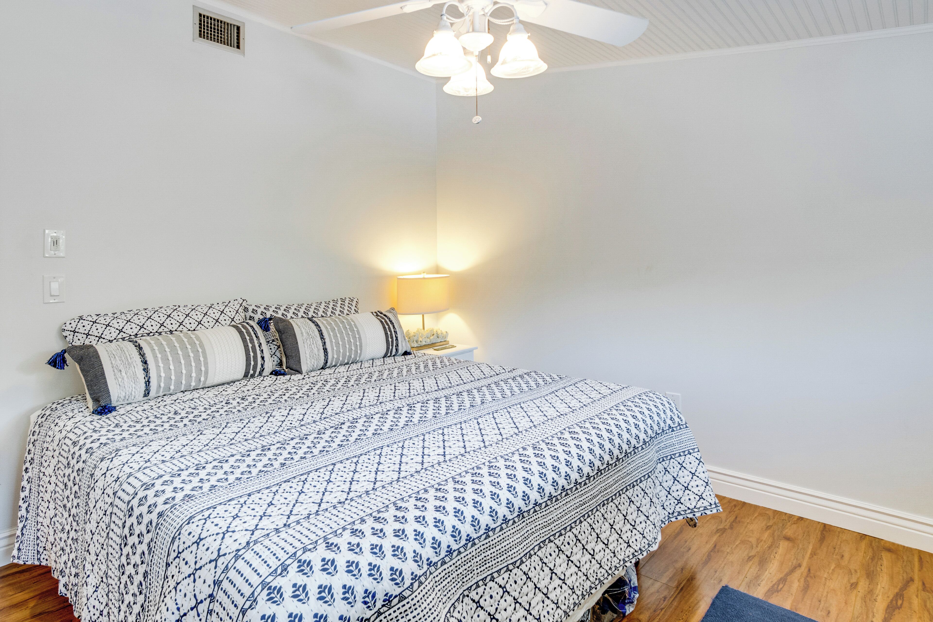 A bedroom with a bed, a nightstand, a lamp, and a ceiling fan.