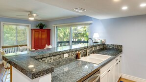 Cozinha com bancada de granito, eletrodomésticos de aço inoxidável e vista para o exterior.