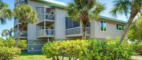 A multi-story hotel with balconies, surrounded by palm trees and a well-maintained lawn.