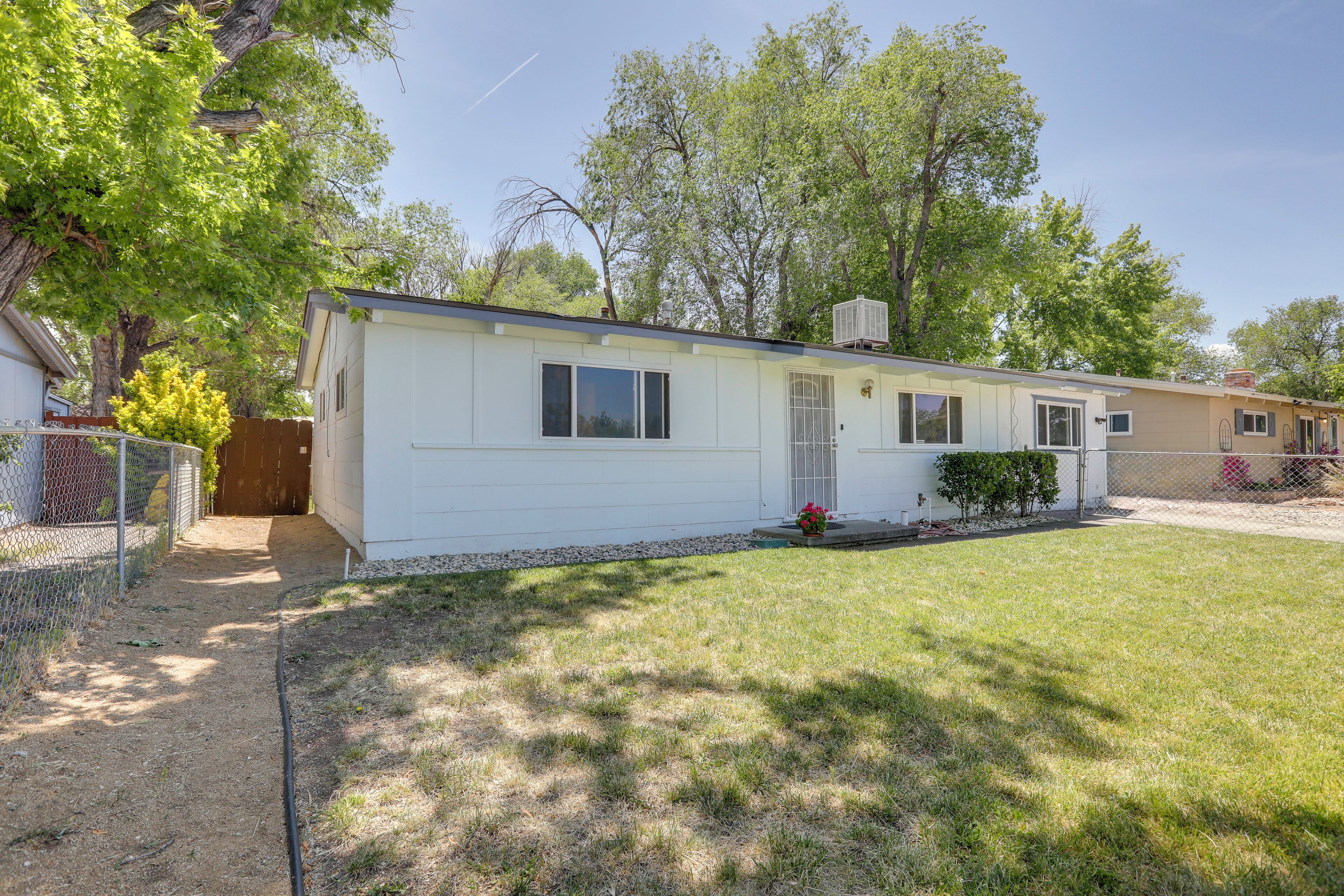 A single-story mobile home with a fenced yard, a small porch, and a clear sky.