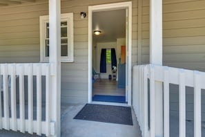 A house entrance with a white picket fence, a door, and a blue mat.