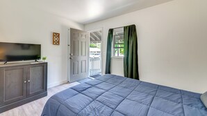 A bedroom with a bed, a TV on a cabinet, a door leading outside, and a window with curtains. - Easy Schroon Lake Living! Close to Marina & Town (Schroon Lake)