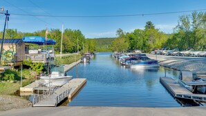 A marina with boats docked, a small building with a blue awning, and a dock extending into the water.