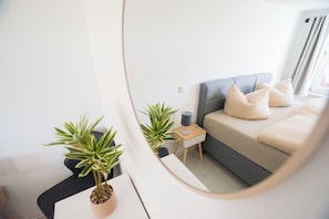 A modern bedroom with a bed, bedside table, lamp, and two potted plants. - Apartment Blankenburg Harz, BERGMOMENT 8 persons, old town, balcony, fireplace, parking lot (Blankenburg (Harz))