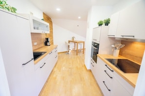 A modern kitchen with white cabinetry, wooden countertops, and a central island. - Apartment Blankenburg Harz, BERGMOMENT 8 persons, old town, balcony, fireplace, parking lot (Blankenburg (Harz))