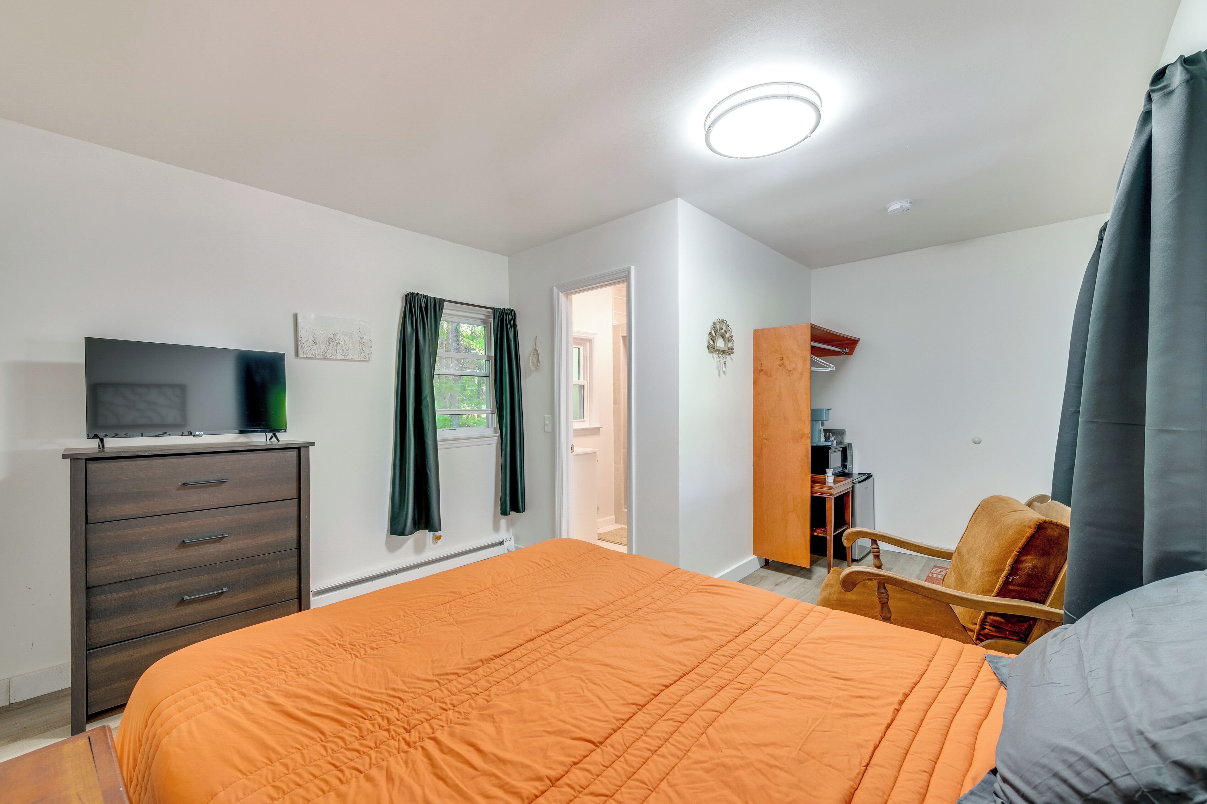 Un dormitorio con cama, cómoda, televisor y armario.
