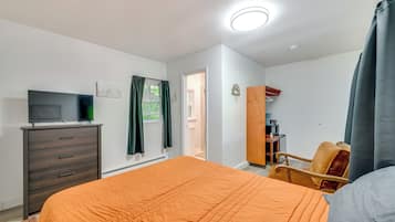 Un dormitorio con cama, cómoda, televisor y armario.