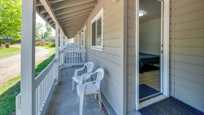 A covered porch with two white plastic chairs, a door leading to a room with a bed, and a small window. - Cozy Room Near Schroon Lake Marina, Town & Beach! (Schroon Lake)