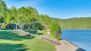 A lakeside property with a grassy area, a wooden bridge, and a small building near the water. - Cozy Room Near Schroon Lake Marina, Town & Beach! (Schroon Lake)