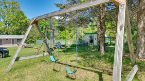 A wooden swing set in a backyard with a house and trees in the background. - Cozy Room Near Schroon Lake Marina, Town & Beach! (Schroon Lake)