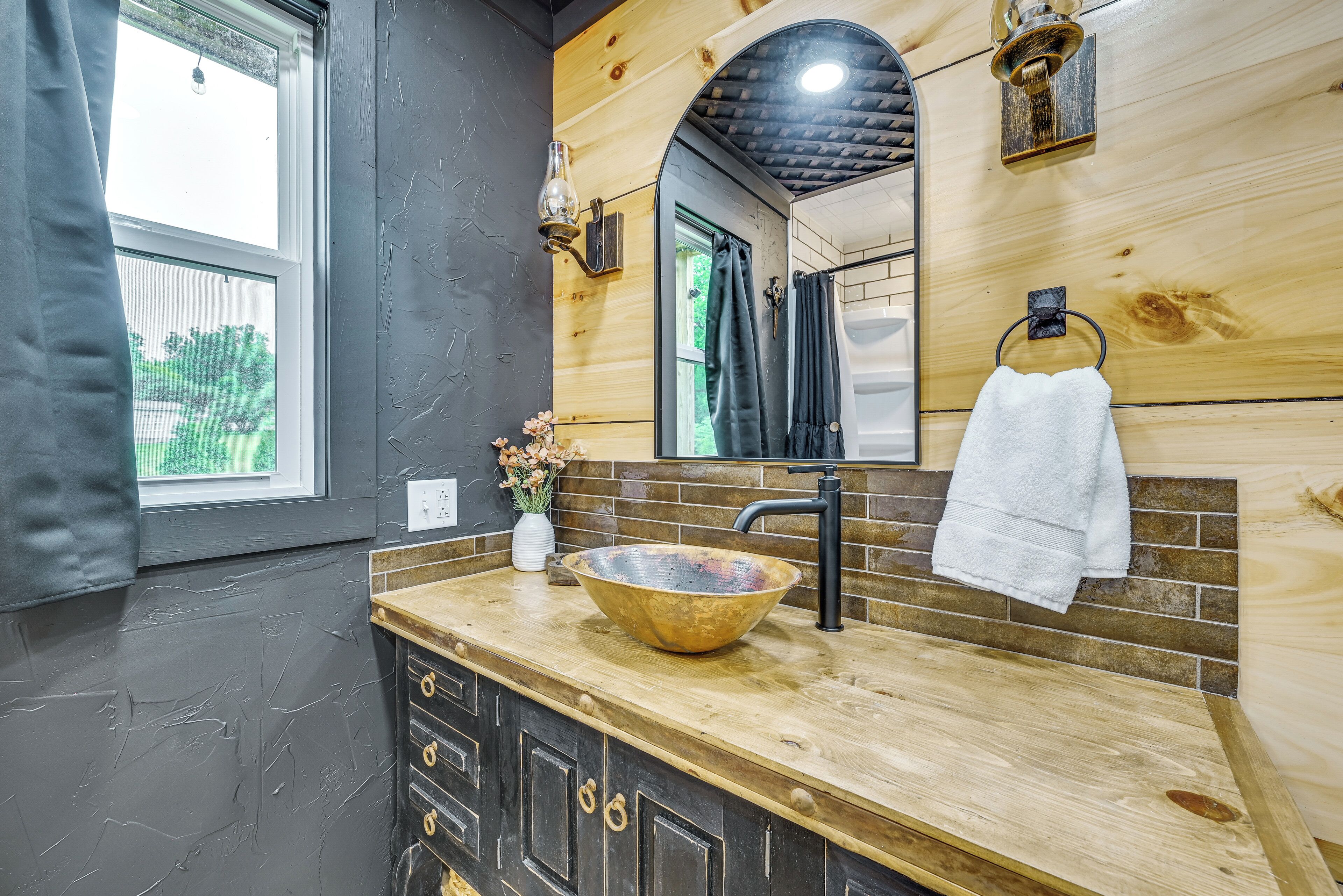 A bathroom with a wooden vanity, a large bowl sink, a mirror, and a towel rack.