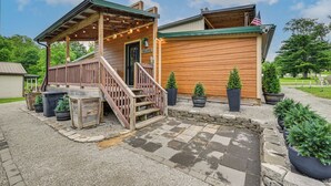 En träbyggnad med en veranda, trappsteg och krukväxter.