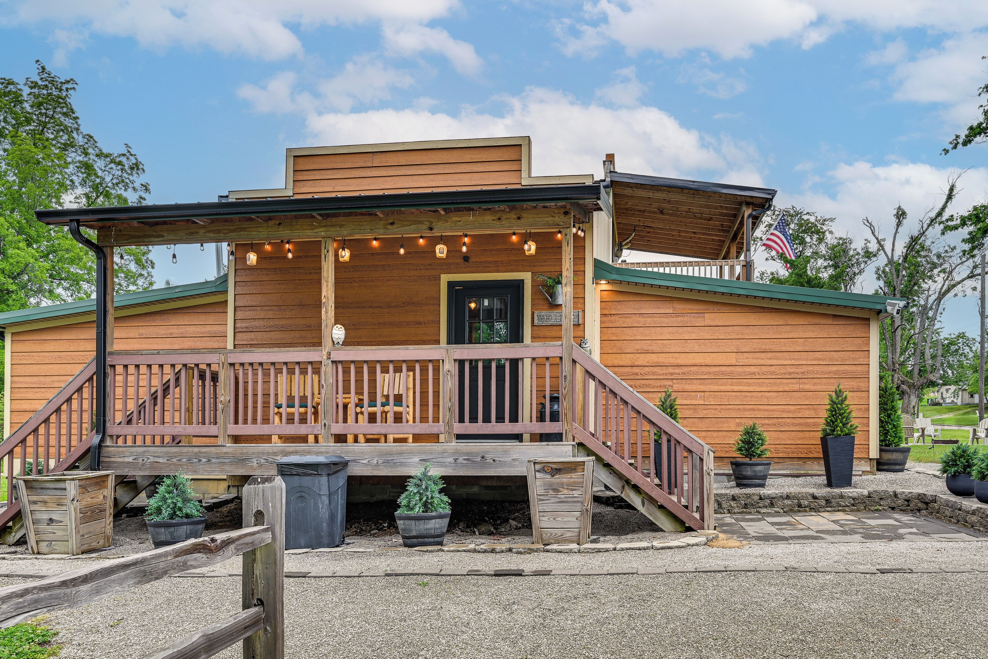 A wooden building with a porch, steps, and potted plants.