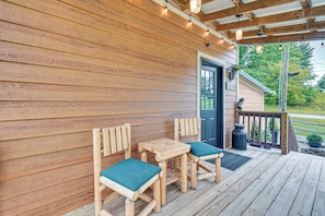 A wooden deck with a table and chairs, a door, and a porch railing.