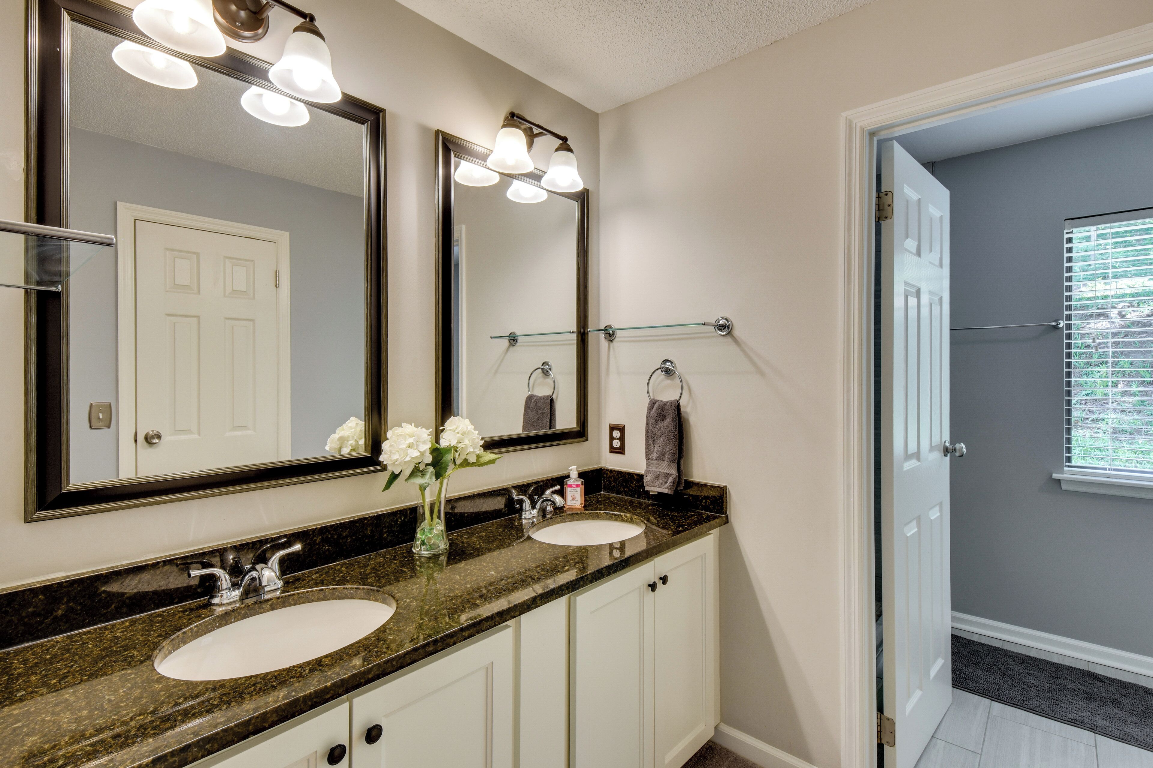 A bathroom with two sinks, a large mirror, and a glass shelf.