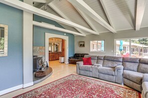 A spacious living room with a large gray sectional sofa, a red patterned rug, and a kitchen in the background. - Palo Cedro Family Retreat: Pool, Nat'l Park, Lakes (Palo Cedro)