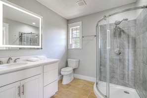 Une salle de bain Ă©quipĂ©e dâune douche, de toilettes, dâun lavabo et dâun miroir.