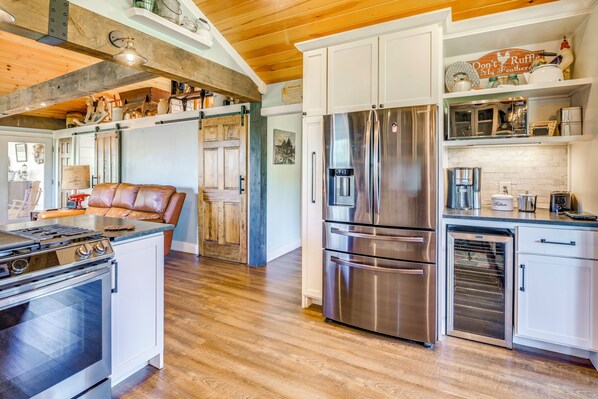 A modern kitchen with stainless steel appliances, white cabinetry, and a wooden ceiling.