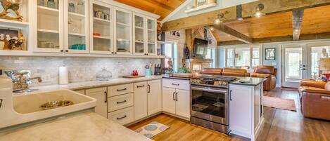 A kitchen with white cabinets, a sink, and a stove.