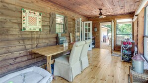 A wooden cabin interior with a wooden table, cushioned seating, a checkered wall decoration, and a door leading outside. - Private Family Home w/ Ocoee River Access (Benton)