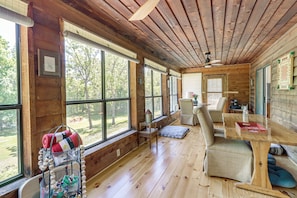 A wooden cabin interior with large windows, a dining table, and a cozy seating area. - Private Family Home w/ Ocoee River Access (Benton)