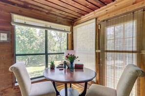 A wooden interior with a round table, two chairs, a vase with flowers, and a bookshelf. - Private Family Home w/ Ocoee River Access (Benton)