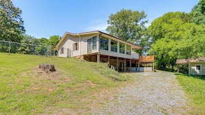 A two-story house with a covered porch, a gravel driveway, and a fenced yard. - Private Family Home w/ Ocoee River Access (Benton)