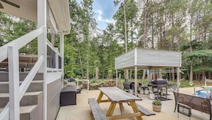 Eine Terrasse mit Holztisch und Bänken, einem Grill und einer überdachten Sitzgelegenheit.