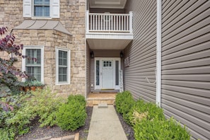 A two-story stone building with a front porch, a small balcony, and a welcome sign.